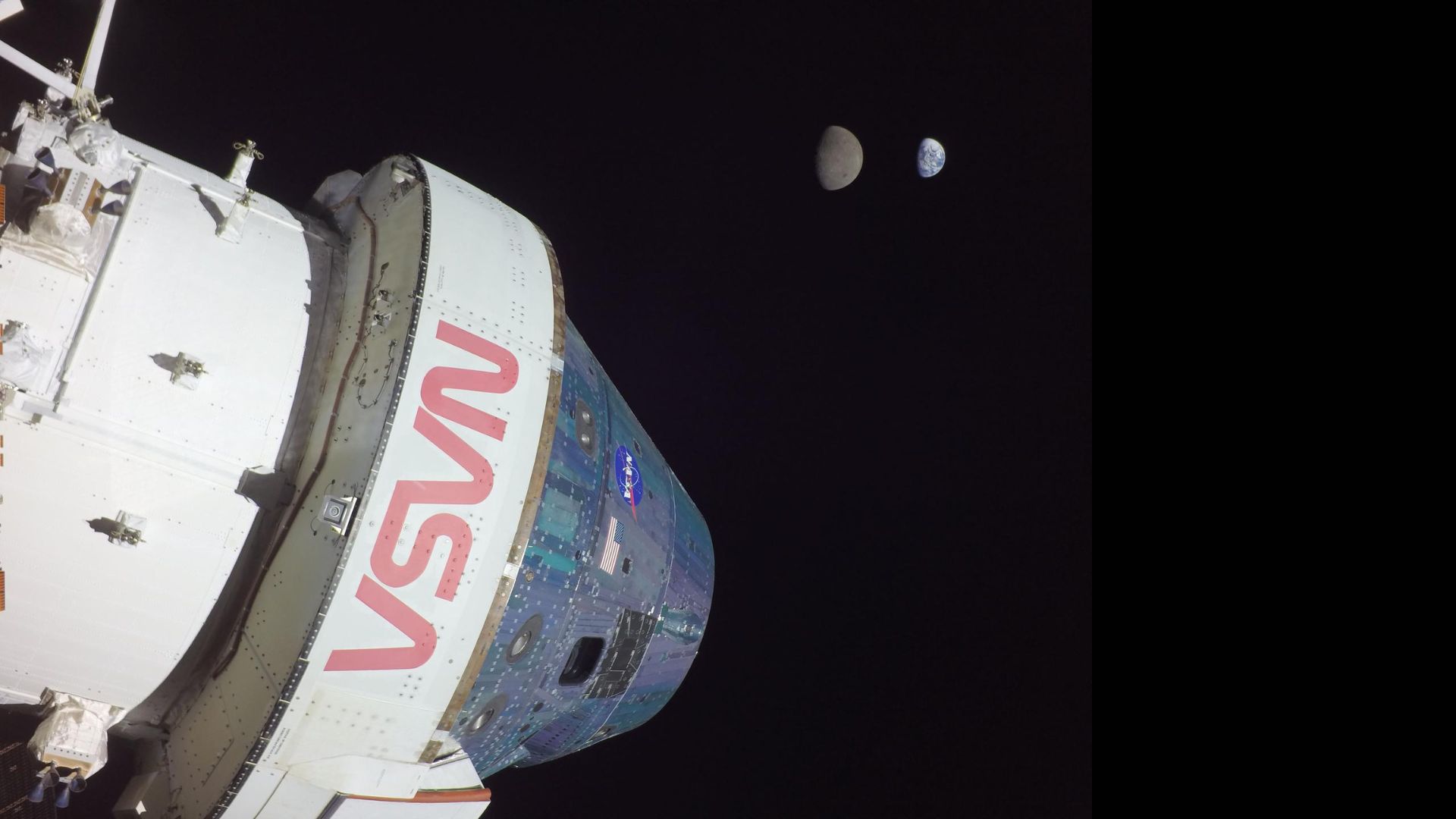 A large white space shuttle labeled in red "NASA" is seen in the darkness of space.