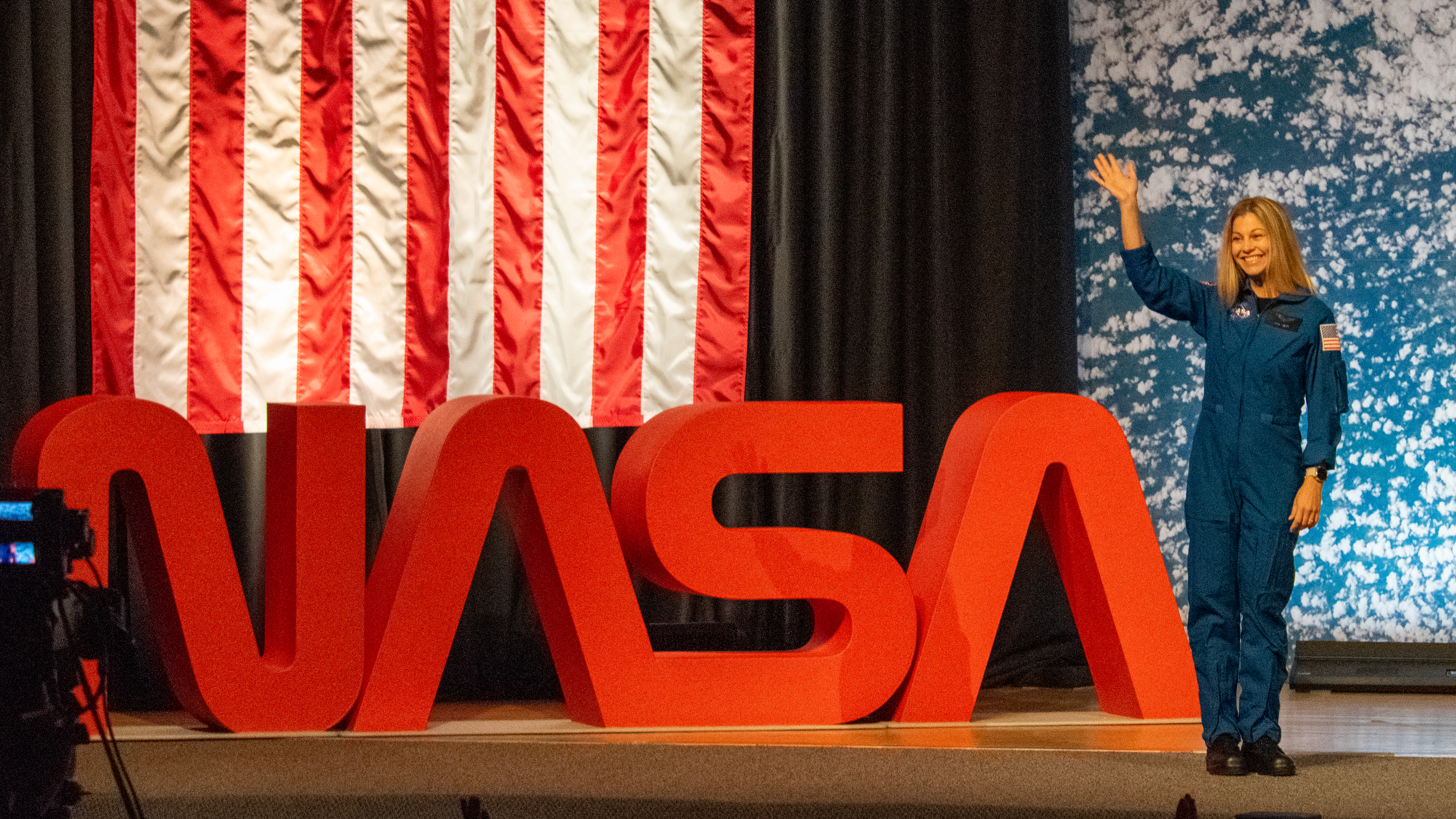 people in blue jumpsuits smile and wave.