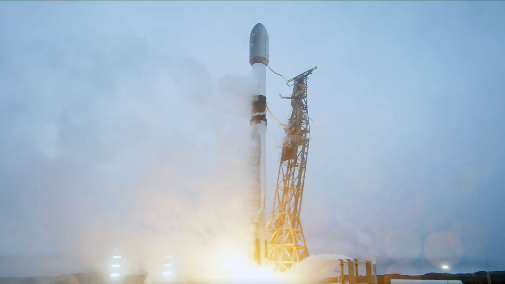 a white and black rocket lifts off into an overcast sky 